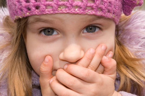 child looking and holding hands over mouth